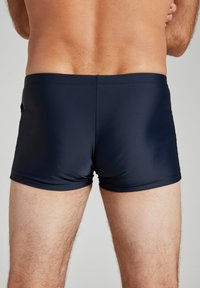 Herren Badehose in dunklem Marineblau, aus dehnbarem Stoff, mit einem schlichten Design, das eine optimale Passform und eine Länge bis zur Mitte des Oberschenkels bietet.