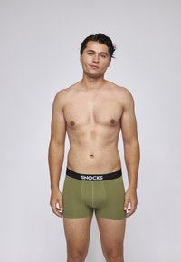 Herren Boxershorts in Olivgrün mit einem schwarzen Bund, auf dem "SNOCKS" steht. Der Stoff wirkt glatt und eng anliegend, entworfen für Komfort.