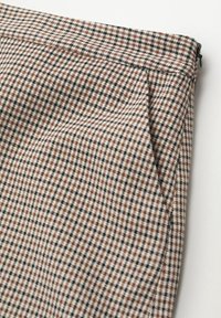 Tissu à motif pied-de-poule taille haute, présentant des couleurs marron, noir et crème, avec une texture lisse et une fermeture éclair.