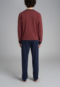 Felpa bordeaux a motivo con pois blu e pantaloni blu scuro. La felpa ha polsini a coste e un colletto rotondo, presentando una vestibilità comoda.