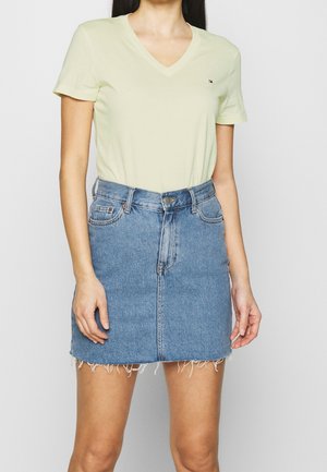 Lichtgele, korte mouwen V-hals t-shirt gecombineerd met een getailleerde blauwe denim mini-jurk, met een rafelrand en een klassiek vijfzakkenontwerp.