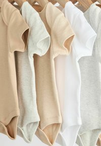 Fem kortärmade bodysuits i beige, ljusgrått och vitt, hänger på en träställning; mjukt tyg och rundade kragar.