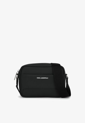 Čierna obdĺžniková crossbody taška vyrobená z matného materiálu, so zipsovým uzáverom, nastaviteľným remienkom a debnárskym logom na prednej strane.