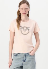Lys rosa bomull T-skjorte med korte ermer, med et teksturert rhinestones smilende ansikt-grafikk i midten. Avslappet passform, rund halsdesign.