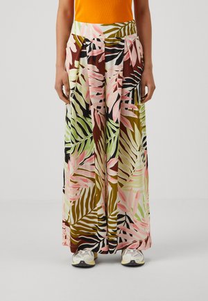 Falda maxi con un estampado de hojas tropicales en verde, rosa y marrón. Fabricada con un tejido ligero y con plisados, combinada con zapatillas deportivas.