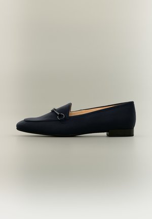 Μαύρο γυναικείο loafers με χαμηλό τακούνι, μεταλλική λεπτομέρεια στο επάνω μέρος, μπεζ εσωτερική επένδυση και λεία σόλα.