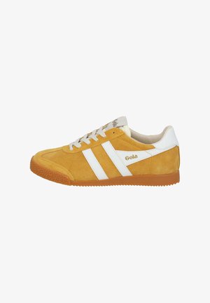 Zapatilla de ante amarilla con rayas blancas, suela de goma texturizada y cordones color crema. Logo presente en el lado y en la lengua.