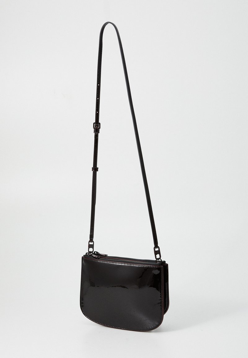 Sac à épaule en cuir verni noir avec une finition lisse, une forme incurvée, une sangle réglable et une fermeture zippée sur le dessus. Design compact.