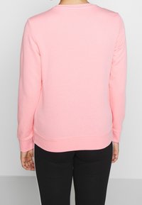 Felpa rosa con maniche lunghe, collo a crew in costine e vestibilità comoda. Tessuto morbido, presenta un orlo dritto e dettagli minimi.