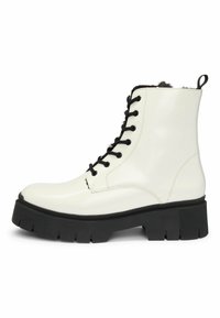 Hvide, blanke læderankelstøvler med sorte snørebånd, kontrasterende sort chunky sål og pelsforing øverst for ekstra tekstur og detaljer.