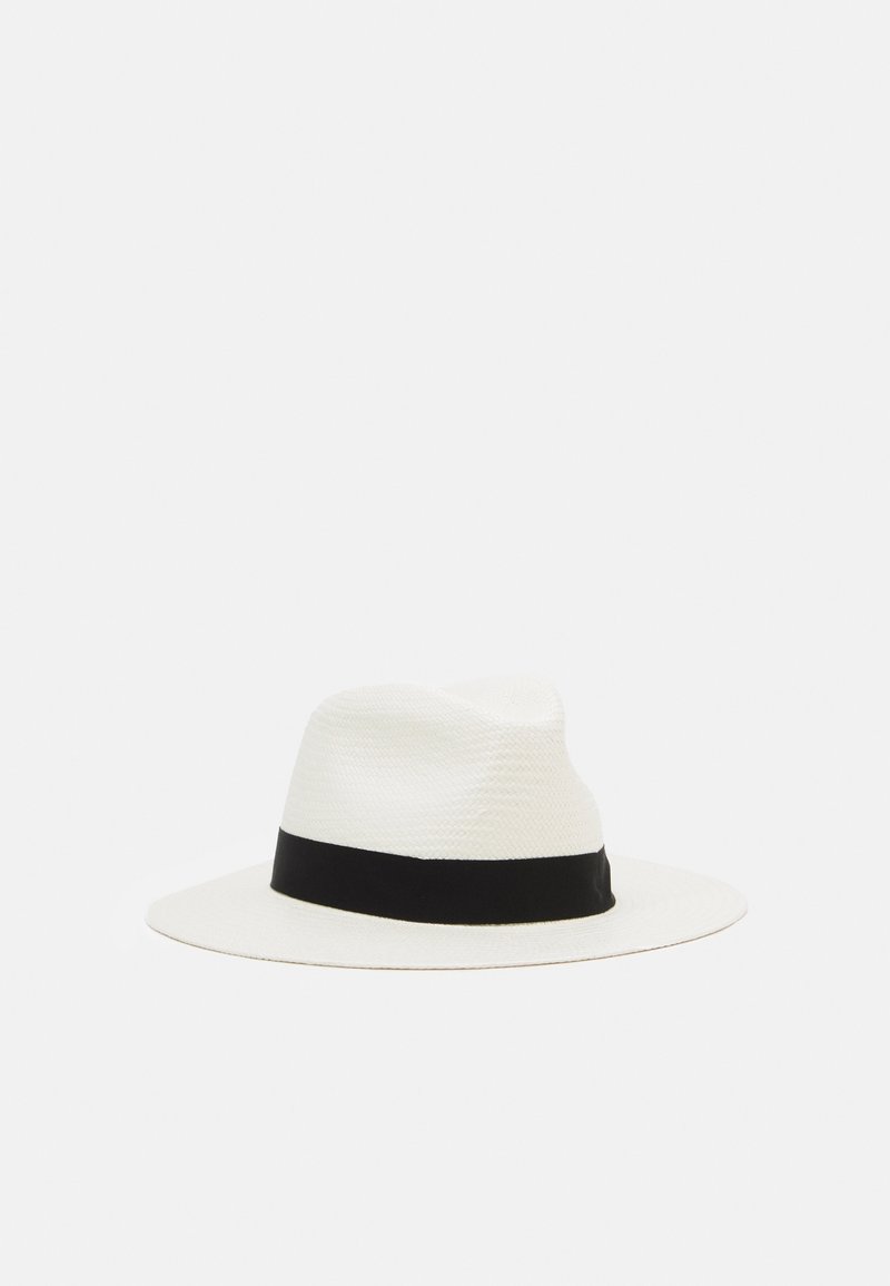 Chapeau fedora blanc à large bord avec un ruban noir autour de la base de la calotte, présenté sur un fond clair uni.