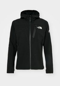 Veste à capuche noire zippée avec le logo The North Face sur la poitrine et le logo Mountain Athletics sur la manche gauche, dotée d'une poche poitrine zippée.