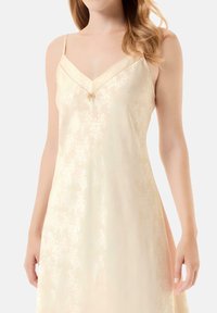 Chemise de satén en amarillo pálido con patrón floral, escote en V, tirantes ajustables delgados y una textura suave y lisa.