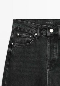 Jeans in denim nero con un classico design a cinque tasche, hardware argentato e un'etichetta in vita. Tessuto testurizzato con un delicato lucido.