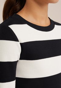 Schwarz-weißer gestreifter Rippstrickpullover mit Rundhalsausschnitt; die Streifen sind gleich breit und zeigen einen strukturierten Stoff.