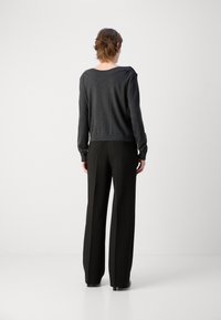 Pull en tricot gris foncé avec un col large associé à un pantalon noir taille haute et à jambes larges. Texture lisse, coupe décontractée et détails subtils.