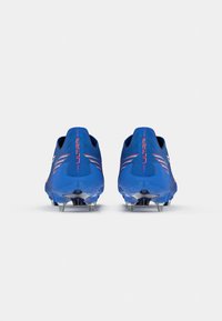 Ein Paar blaue Fußballschuhe mit Metallstollen und dem Schriftzug "ULTRA" an der Ferse, von hinten auf einem schlichten weißen Hintergrund gezeigt.