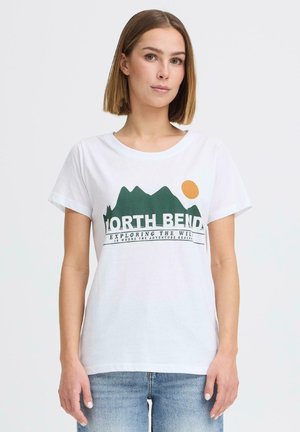 Kvinne med rett brunt hår har på seg hvit T-skjorte med grønt fjell og oransje solgrafikk og teksten "North Bend" og blå jeans.