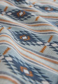 Musterstoff mit blauen, orangen und weißen geometrischen Designs. Weiche Textur mit diagonalen Streifen und einer Mischung aus Rauten- und Zickzackmotiven.