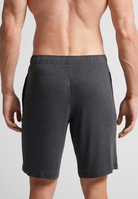 Mörkgrå herrsportshorts, tillverkade av mjukt tyg, med midjeband av elastisk modell och sidofickor, med en slät yta och knälång klipp.