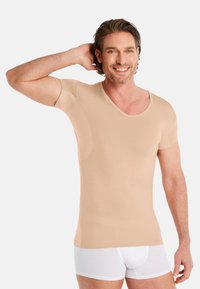 Beige short-sleeve V-neck shirt made of smooth fabric, featuring side seams and reinforced stitching for added structure.
