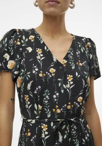 Robe noire à fleurs avec manches courtes bouffantes, un décolleté en V et des détails de boutons. Le motif comprend des fleurs jaunes et roses avec des feuilles vertes.