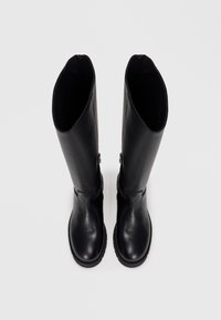 Bottes noires en cuir, montant jusqu'aux genoux, avec une finition lisse, des bouts arrondis et des semelles plates. Dotées d'une fermeture éclair sur le côté pour un enfilage facile.