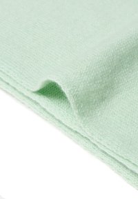 Hellgrüner Strickstoff mit weicher Textur und feinem Muster. Die Ränder sind sauber verarbeitet und zeigen eine leichte Faltung.