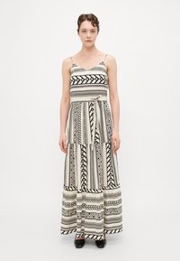 Rochie maxi cu model alb și negru, cu bretele subțiri, având designuri geometrice, un corset ajustat și fustă evazată.