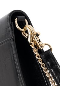 Detal detaliczny czarnej skórzanej torebki, z błyszczącym złotym metalowym zapięciem, łańcuszkowym paskiem oraz gładką fakturą i prostymi liniami.