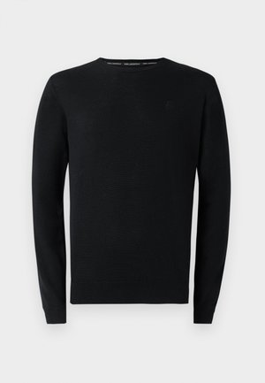 Suéter negro de punto con cuello redondo, mangas largas y puños acanalados. Presenta un sutil logotipo en el pecho. Tejido texturizado con un acabado suave.