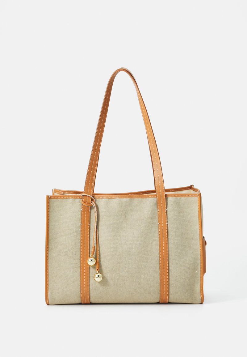 Beige καμβάς τσάντα tote με καφέ δερμάτινους ιμάντες, χρυσές μεταλλικές λεπτομέρειες και κλείσιμο με κορδόνι που περιλαμβάνει διακοσμητικά κουδουνάκια.