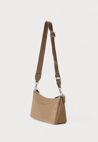 Hnedá látková kabelka s zakriveným tvarom, nastaviteľný popruh s potlačou loga, strieborné kovanie a zipsové uzatvorenie.