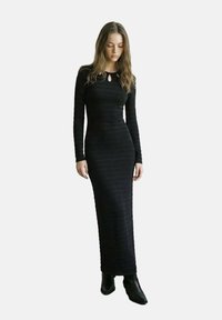 Schwarzes, langärmeliges Kleid mit einem Schlüsselloch-Detail am Ausschnitt, aus strukturiertem Material, körperbetonte Silhouette, knöchellanger Schnitt.