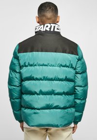 Teal puffer jacket with black shoulder panel, featuring quilted sections, high collar, and branded neck detail. Smooth, shiny texture.