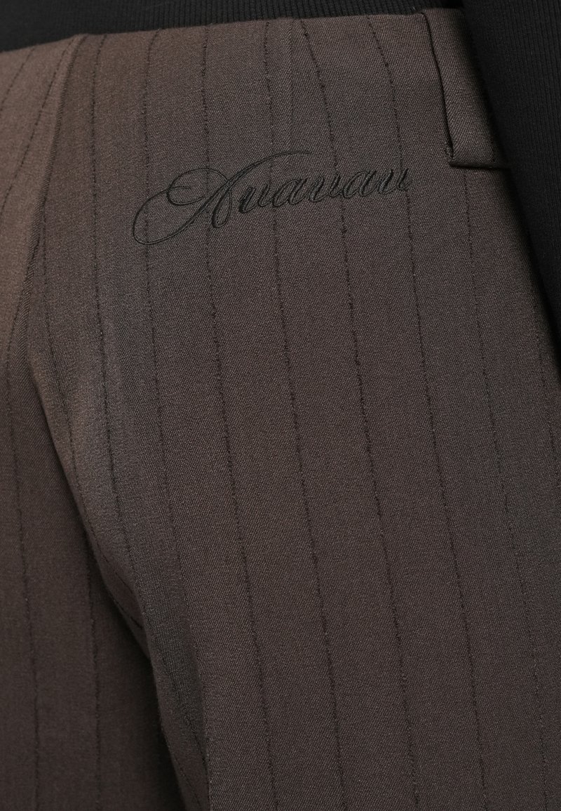 Pantalons bruns à rayures, en tissu lisse, avec un logo brodé. Le design comprend une coupe ajustée et un subtil éclat.