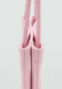 Rosa stofpose med to sidetekster, glat tekstur og struktureret form. Har rene sømme og ingen synlige detaljer eller mønstre.