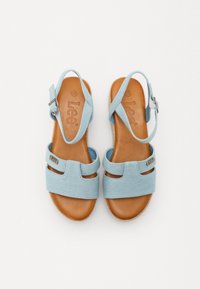 Sandálias de denim azul claro com duas tiras largas, palmilha de couro castanho, tira ajustável no tornozelo e um detalhe de logotipo discreto na lateral.