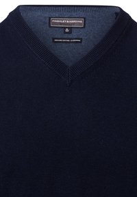 Marynarski sweter w serek wykonany z mieszanki organicznej bawełny i kaszmiru. Charakteryzuje się gładką teksturą oraz ribbowanym dekoltem. Metka widoczna wewnątrz.