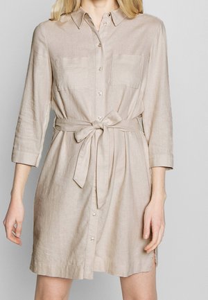 Vestido camisa de lino beige con cuello, mangas largas, dos bolsillos en el pecho, cierre de botones en el frente y cinturón en la cintura, con un corte recto y aberturas laterales.