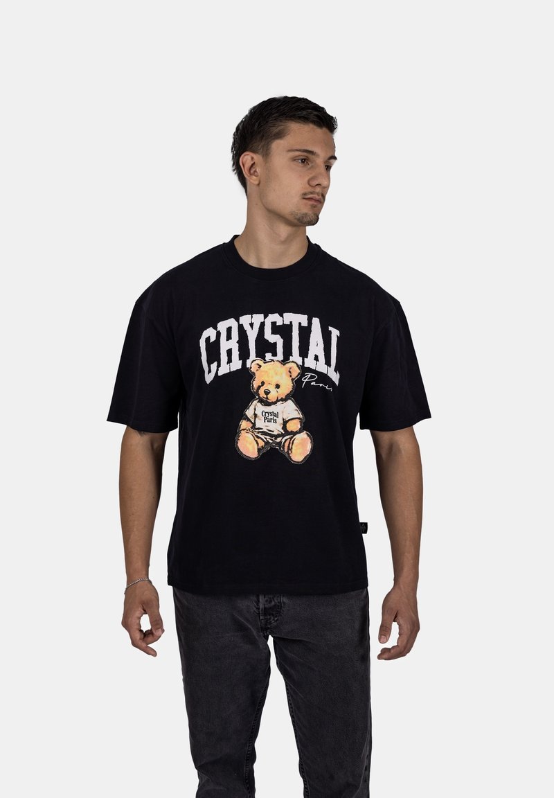 Černé bavlněné tričko s grafikou medvídka a textem "CRYSTAL" v bílé barvě na jednobarevném pozadí.