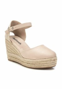 Zapato de cuña de esparto beige con parte superior lisa, tira en el tobillo y suela trenzada de yute. Presenta una punta redondeada y plantilla acolchada.