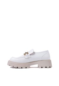 Scarpe slip-on bianche in pelle sintetica con una spessa suola piattaforma beige e dettagli in hardware dorato sul davanti. Design con punta arrotondata.
