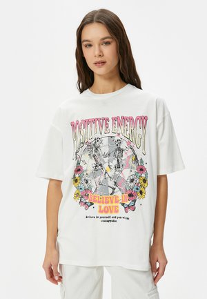 Weißes Baumwoll-T-Shirt mit einem bunten Grafikdruck, der Skelette, Blumen und Text zeigt. Übergröße Schnitt mit kurzen Ärmeln und rundem Ausschnitt.