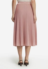 Fållad midi kjol i ljusrosa tyg med en subtil skimrande yta, med en midja och en kjollängd som går till knäna.