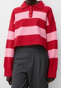 Red and pink striped cropped sweater with a collar and three-button placket. Made of soft fabric; features long sleeves and ribbed cuffs.