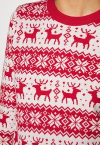 Maglione lavorato a maglia rosso e bianco con righe di renne e motivi di fiocchi di neve sul petto e sulle maniche.