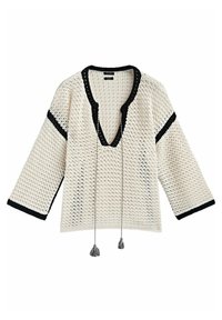 Pull en crochet crème avec des accents noirs. Présente un décolleté en V profond, des manches larges et des franges au niveau du col. Motif texturé sur l'ensemble.