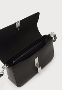 Borsa a mano in pelle nera con superficie texturizzata, hardware in tono argento e chiusura magnetica. L'interno presenta una tasca con zip e uno slot per carte.