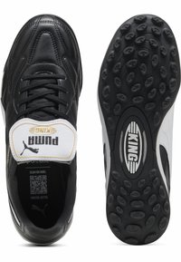 Botas de fútbol de cuero negro con acentos en blanco y gris, que cuentan con una lengüeta acolchada etiquetada "PUMA KING" y suelas de goma texturizada.